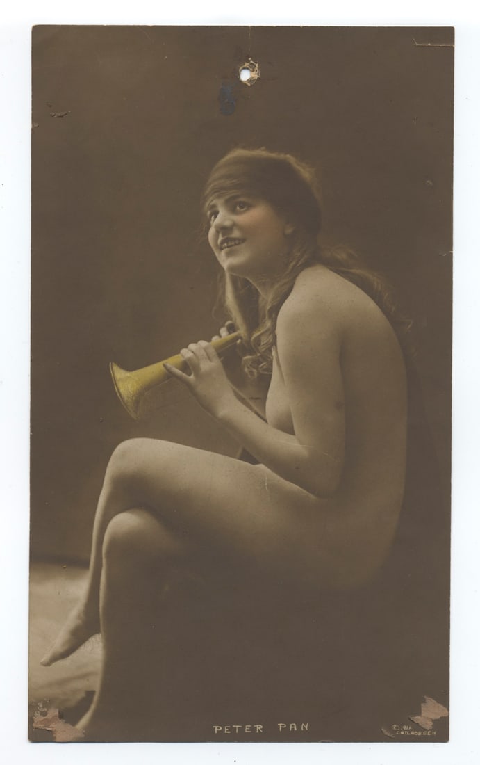 Vintage Artistic Nude Photography: This photograph, measuring 5 x 9 inches, portrays a whimsical scene inspired by the tale of Peter Pan. The subject, a nude young woman with flowing hair, is seated while playfully holding a small trum