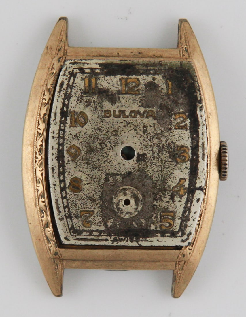 Vintage Bulova Watch Case: This vintage Bulova watch features an intricately designed gold-tone case with a Swiss-made movement. The face of the watch is loose, and the hands are missing, revealing the mechanism beneath. The ba