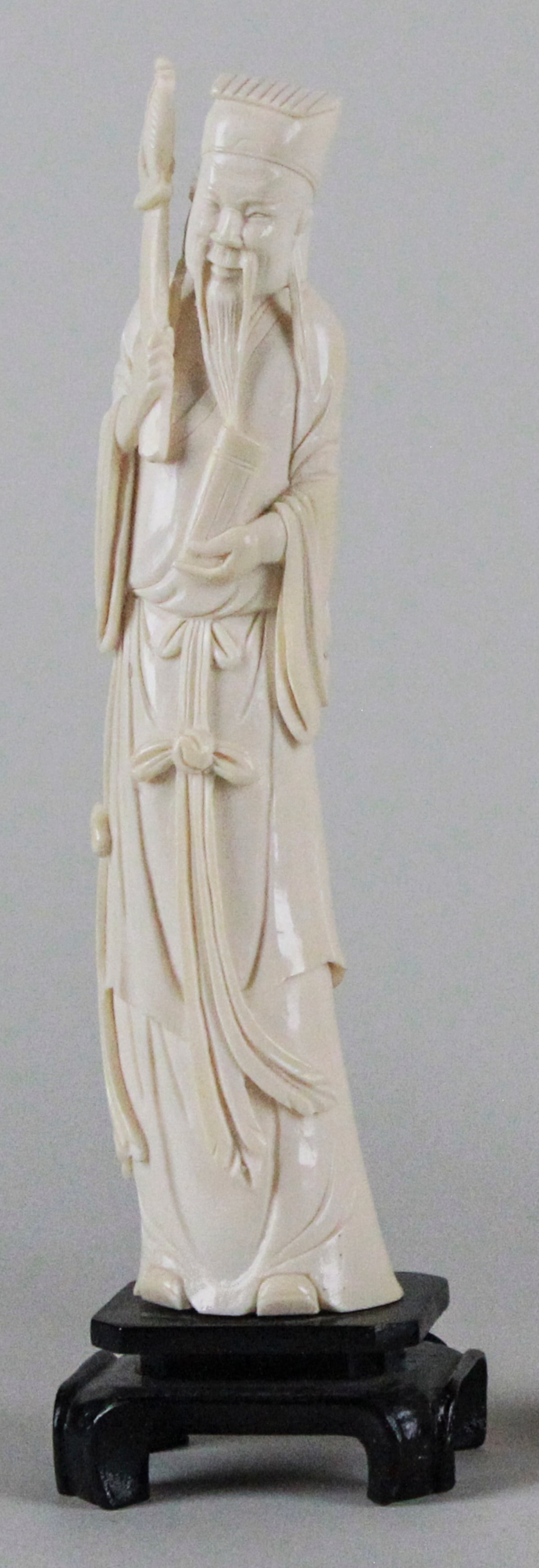 Antique Ox Bone Scholar Statue: This elegant antique ox bone carving depicts a scholar, standing on a traditional wooden base. The intricately detailed figure stands at 11 inches tall, 3 inches wide, and 2.5 inches deep. The statue