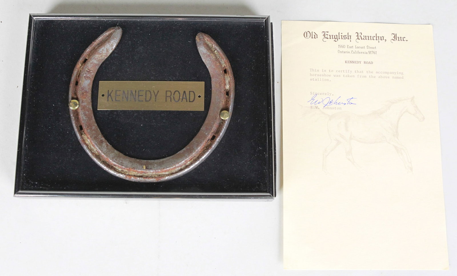 Framed Horseshoe of Kennedy Road with Signed Authentication: A framed horseshoe from Kennedy Road, a champion thoroughbred. Comes with a certificate of authenticity from Old English Rancho, signed by E.W. Johnston. Please note: Pasadena Auction House provides C