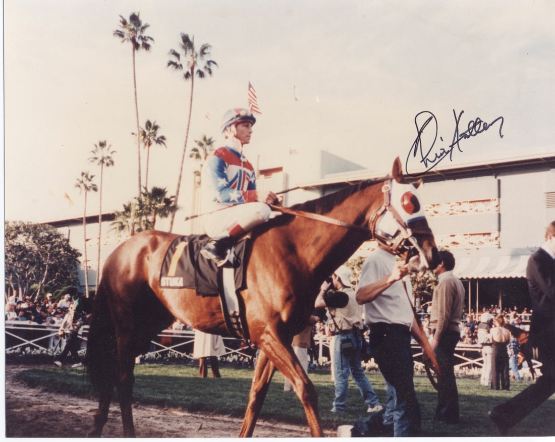 Signed 8x10 Photo / Chris Antley on Stuka at Santa Anita: Color photograph signed by Hall of Fame jockey Chris Antley, shown mounted on Stuka in full silks before the 1994 Santa Anita Handicap. The image captures a quiet pre-race moment on the track, with An