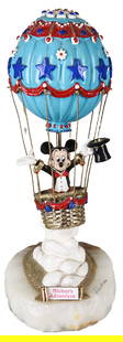 1990 Disney “Mickey’s Adventure” Sculpture by Ron Lee – Limited Edition 954/2750: This vibrant and whimsical sculpture titled Mickey’s Adventure by Ron Lee features Mickey Mouse dressed in formal attire, rising in a patriotic hot air balloon adorned with red, white, and blue