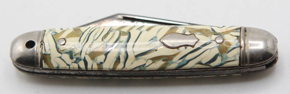 Vintage Pocket Knife with Faux Ivory Celluloid Handle and Fish-Shaped Inlay: This vintage pocket knife features a 4-inch closed length and sports a unique faux ivory celluloid handle with an eye-catching marbled pattern in beige, green, and cream tones. Accented with a polishe