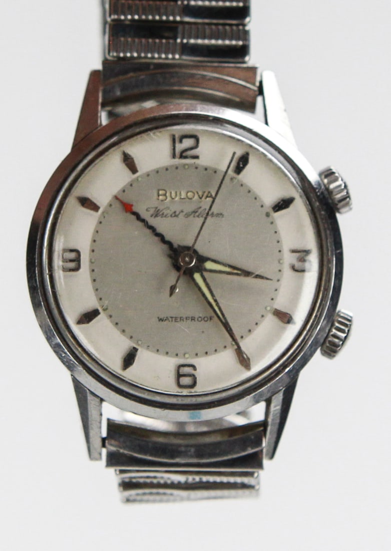 Vintage Bulova Wrist Alarm Stainless Steel Watch: This vintage Bulova wristwatch features a classic stainless steel case and band, with a light silver-tone dial marked "Bulova Wrist Alarm" and "Waterproof." Notable for its dual crown design, this pie