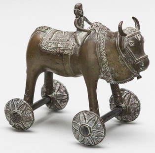 Antique Indian Brass Ox Rider Wheel Toy: Charming antique Indian brass ox figurine with a rider, designed as a wheeled toy. The piece features intricate hand-etched patterns on the ox’s body and saddle, and a stylized rider with
