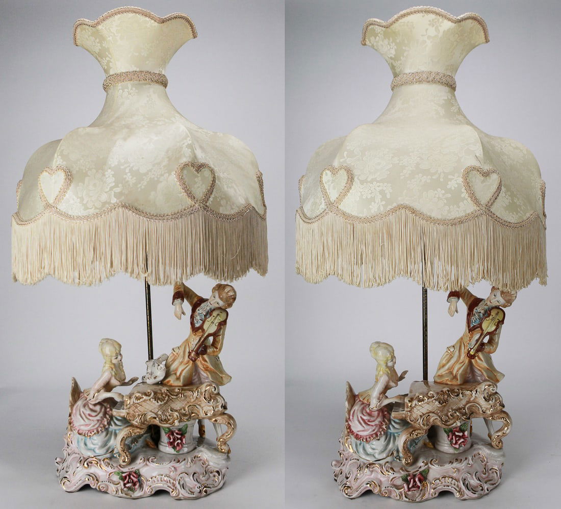 Pair of Vintage Capodimonte Italian Porcelain Lamps with Figurines and Fabric Shades: This pair of vintage Capodimonte Italian porcelain lamps showcases finely detailed hand-painted porcelain figures of a lady at a piano and a gentleman playing the violin, set on ornate Rococo-style ba