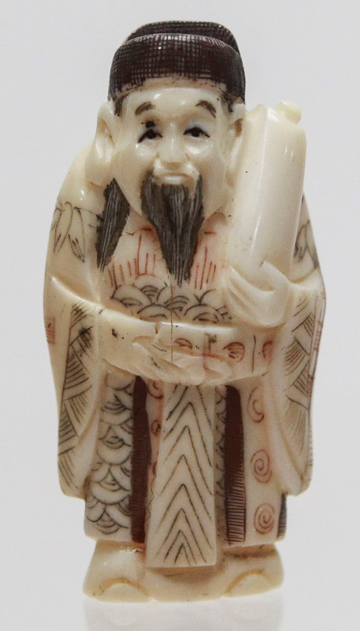 Vintage Japanese Carved Scholar Holding Scroll Netsuke Signed: Vintage Japanese carved netsuke depicting a smiling bearded scholar or official standing in flowing robes while holding a large scroll under one arm and another scroll across his hands. The robe is de