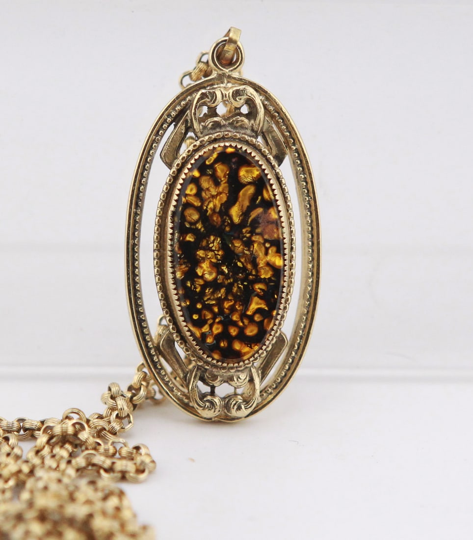 Whiting & Davis Gold-Tone Pendant Necklace with Confetti Lucite Cabochon: Vintage Whiting & Davis gold-tone pendant necklace featuring an ornate openwork oval frame set with an amber and black confetti Lucite cabochon. The pendant measures approximately 2.25 x 1.25 inches a