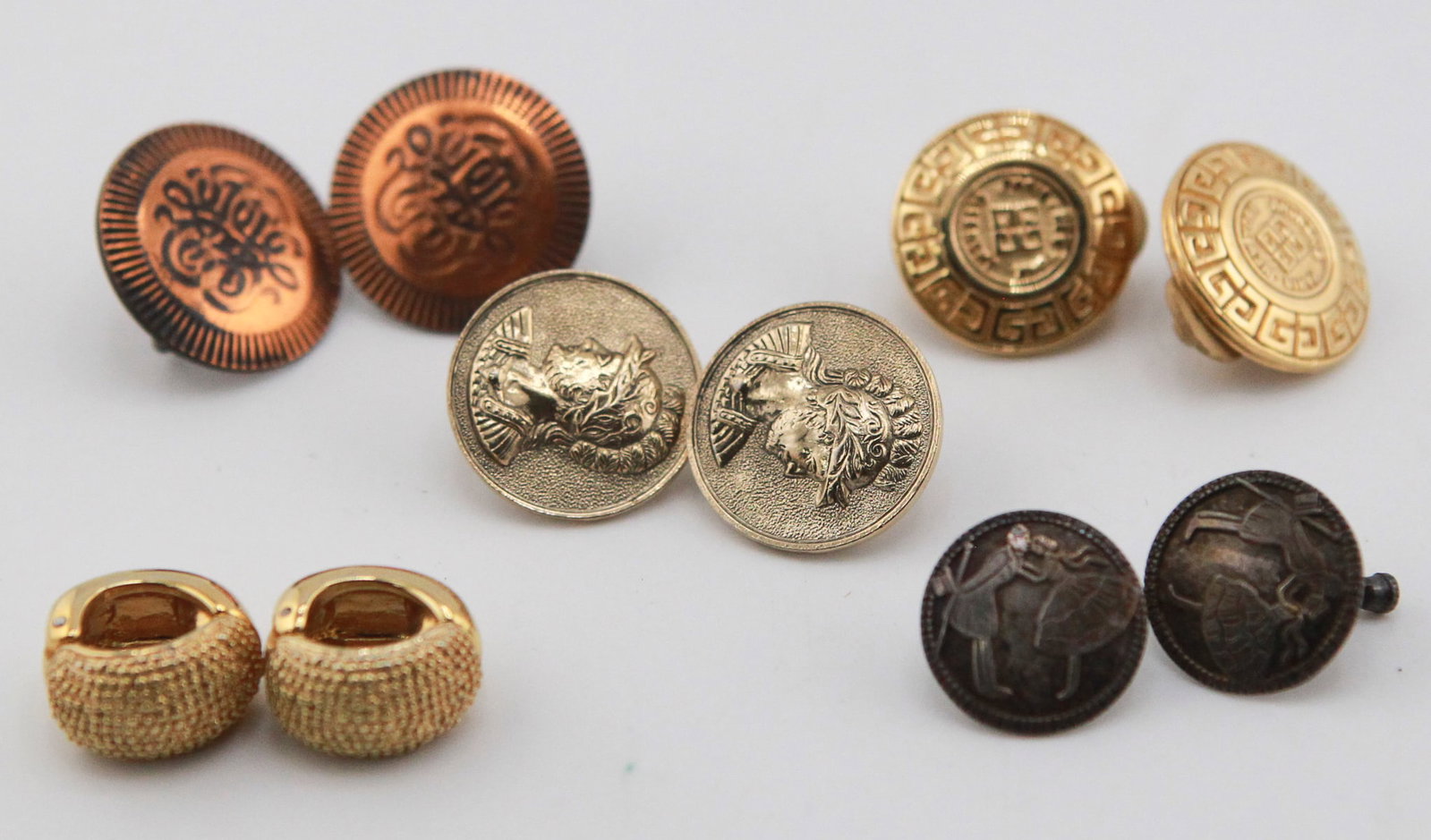 Lot of 5 Pairs of Vintage Clip-On Earrings: Collection of five pairs of vintage clip-on earrings in a variety of styles and finishes. Includes textured gold-tone domed earrings, copper-tone repoussé-style discs, Greek key motif gold-tone discs