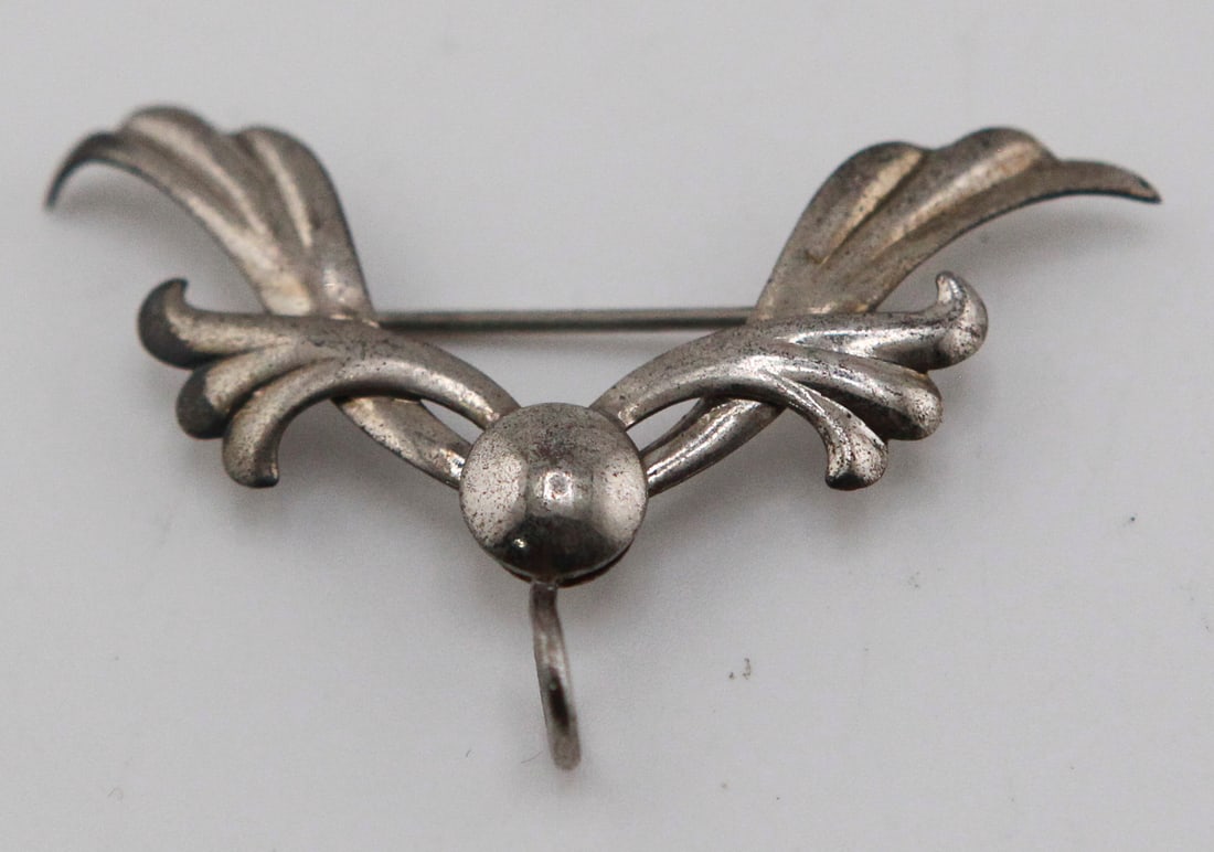 Sterling Silver Brooch Pendant: Sterling silver convertible brooch pendant featuring an elegant stylized foliate scroll design. Constructed with a pin back and integrated pendant bail, allowing it to be worn as either a brooch or a