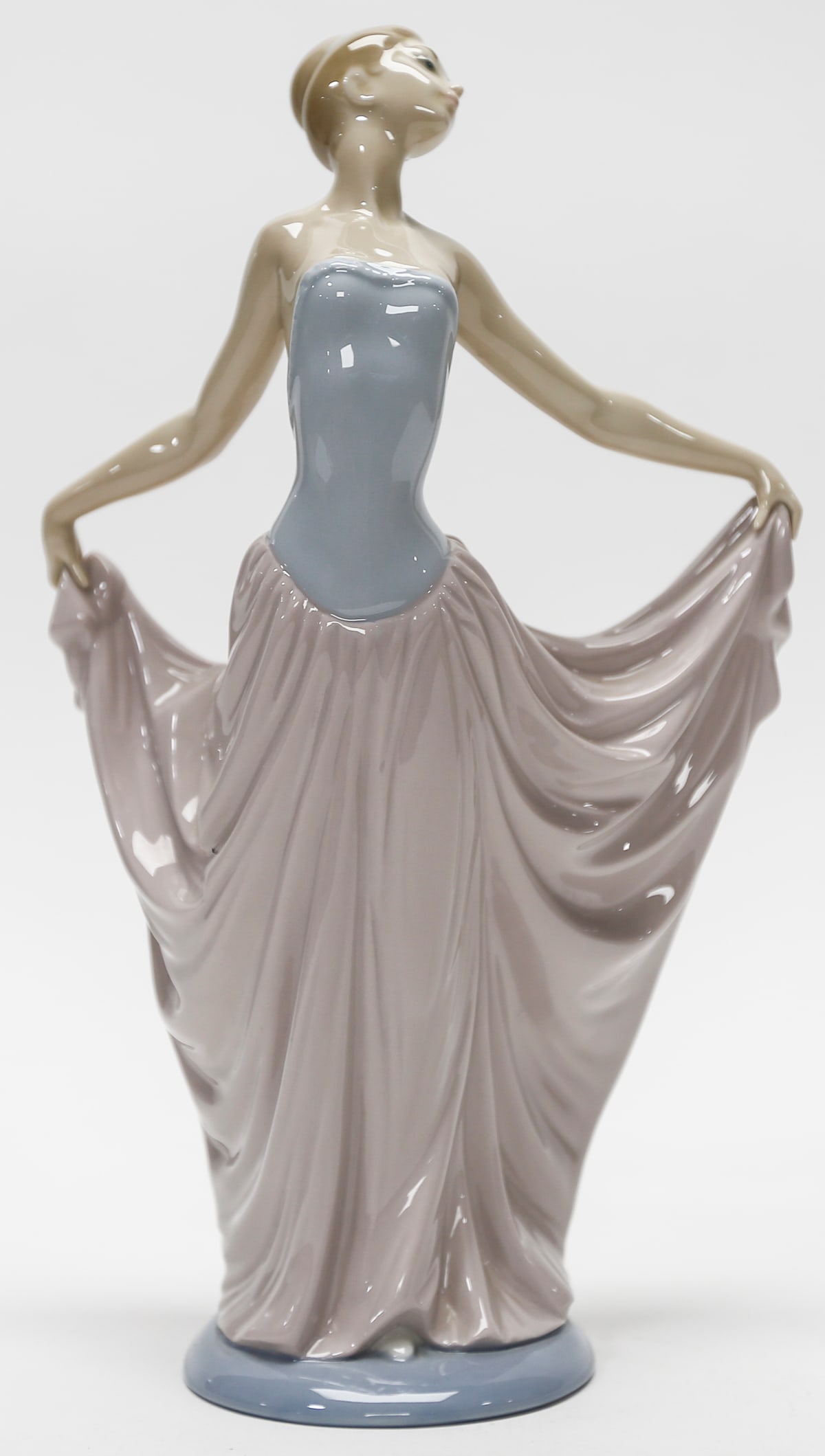 Lladró Elegant Lady Porcelain Figurine: Lladró glazed porcelain figurine depicting an elegant young woman in a graceful dancing pose, holding the sides of her flowing lavender skirt. The figure features a pale blue fitted bodice, delicatel