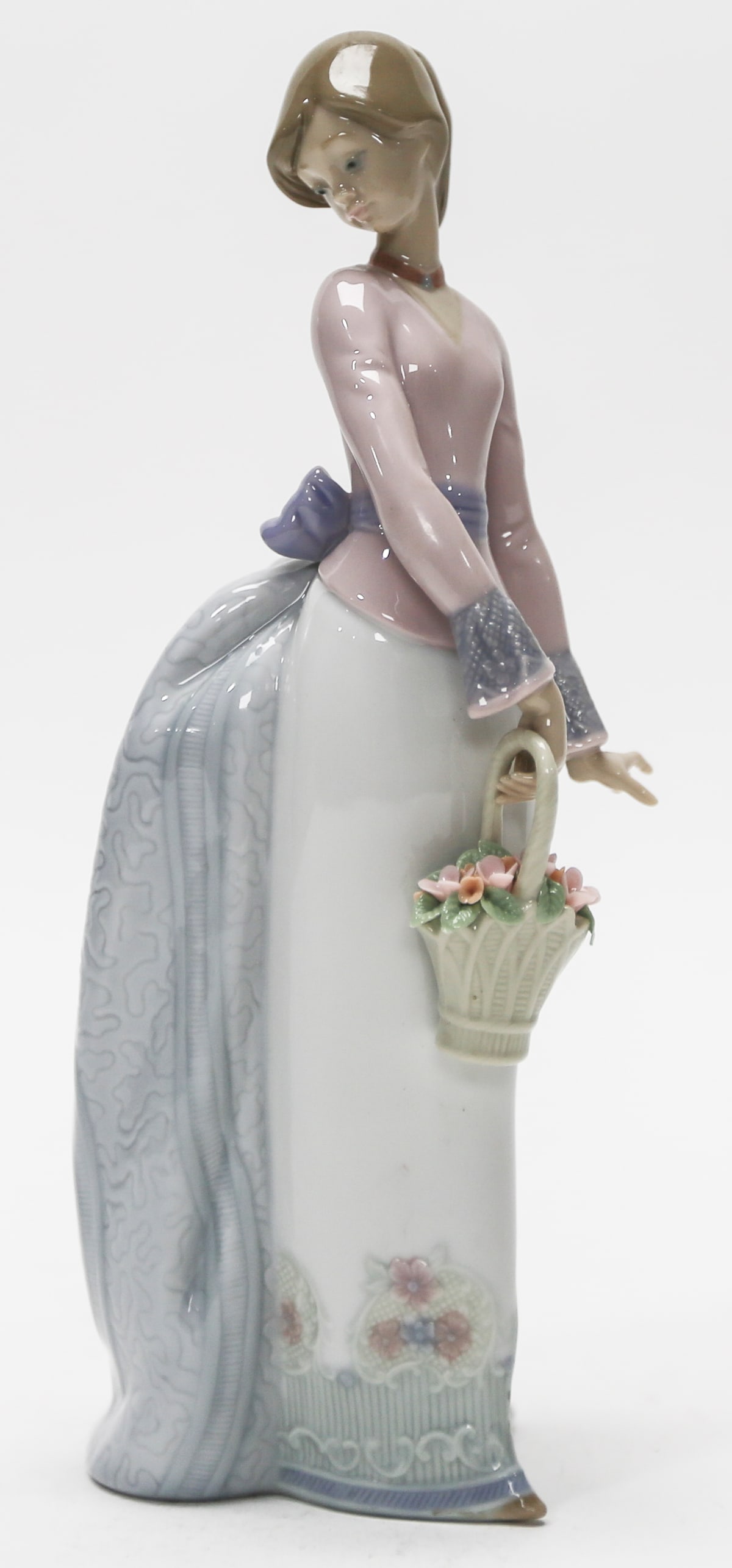 Lladró Lady with Flower Basket Figurine: Elegant Lladró porcelain figurine depicting a young woman in a flowing pastel gown carrying a basket of delicate pink flowers. Finished in soft pink, blue, lavender, and green tones with intricate