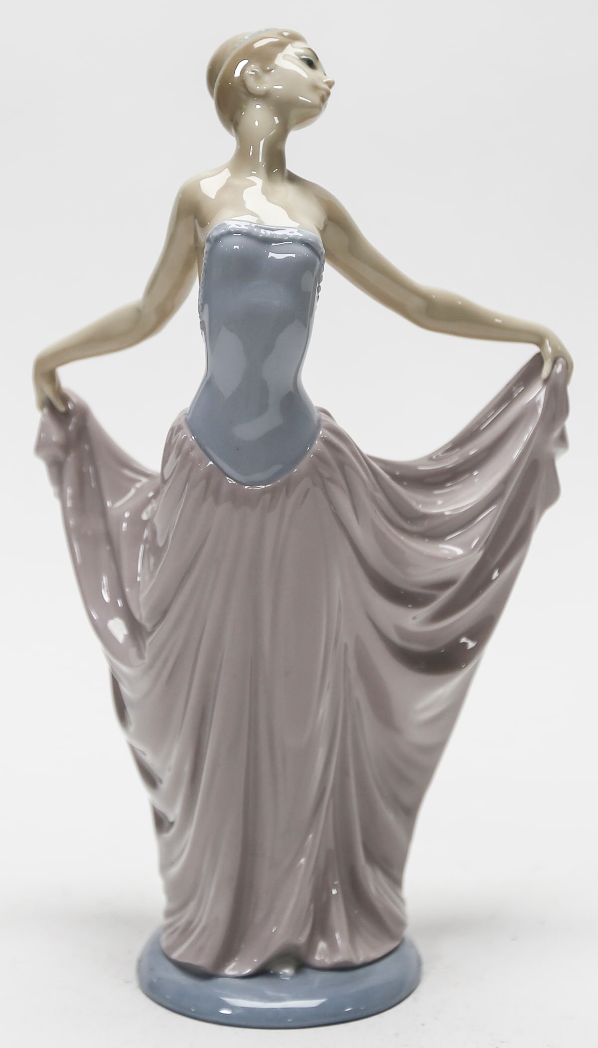 Lladro The Dancer Porcelain Figurine No. 5050: A retired Lladro glazed porcelain figurine titled The Dancer, model No. 5050, depicting an elegant ballerina holding the sides of her flowing lavender skirt while wearing a pale blue bodice. Designed