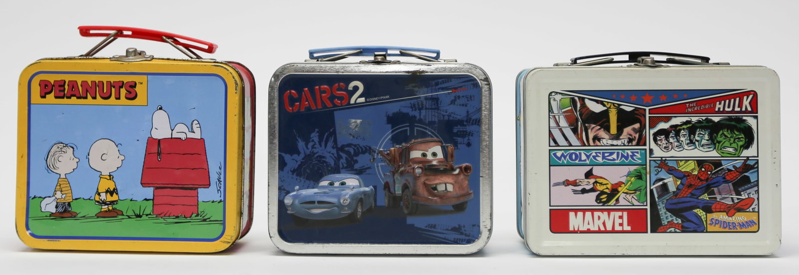 Lot of Three Character Tin Lunch Boxes: A lot of three miniature metal lunch boxes featuring Peanuts, Disney Pixar Cars 2, and Marvel comic characters including Spider-Man, Wolverine, and the Incredible Hulk. Each box has colorful printed d
