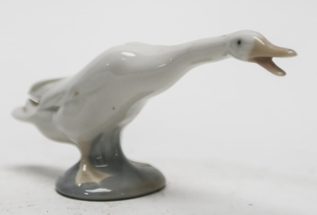 Lladro Daisa Porcelain Goose Figurine: Glazed porcelain figurine depicting a long-necked goose with open beak and raised wings, finished in soft white and gray tones on an oval base. Blue Lladro Daisa Made in Spain mark and impressed model