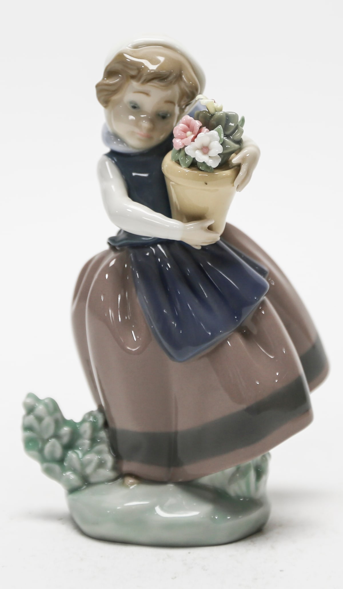 Lladro Spring Is Here Porcelain Figurine No. 5223: Retired Lladro glazed porcelain figurine titled Spring Is Here, model No. 5223. The composition depicts a young woman in traditional country attire carrying a tan flowerpot filled with individually mo