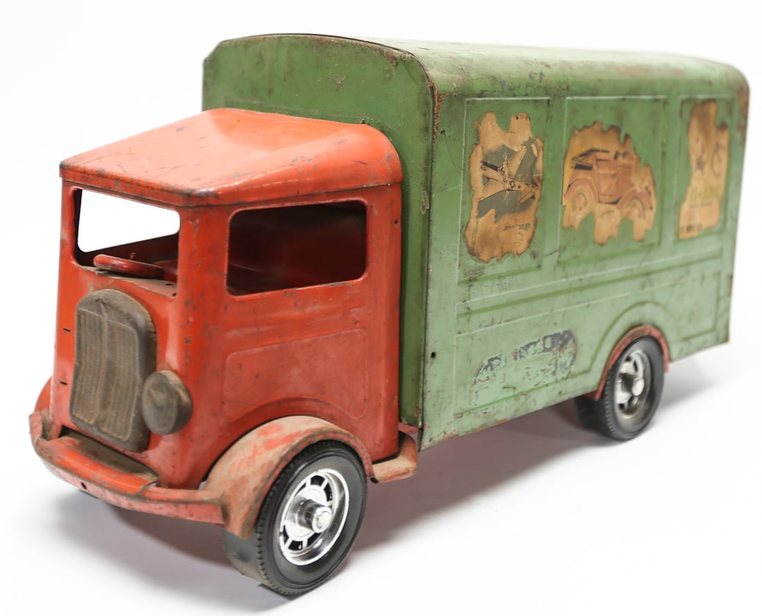 Vintage Tri-ang Pressed Steel Delivery Truck: Vintage Tri-ang pressed steel delivery truck by Lines Bros. Ltd., featuring a red cab, green enclosed cargo body, opening rear doors, steering wheel, rubber tires, and original-style illustrated adver