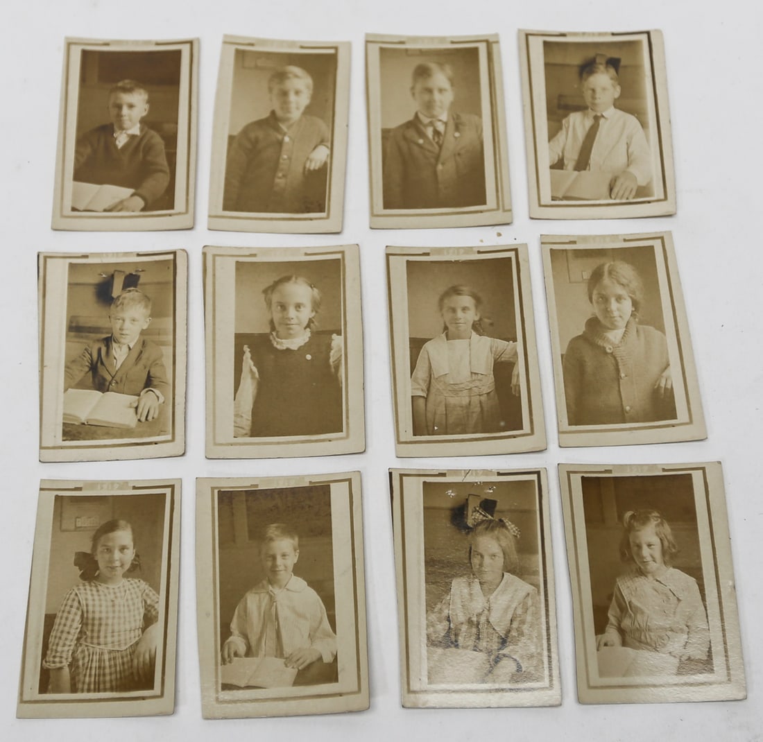 Vintage Schoolchildren Photographs Lot of 12: A collection of 12 vintage black and white school photographs depicting individual boys and girls posed at their desks, several holding open books. The reverse sides include handwritten names identify