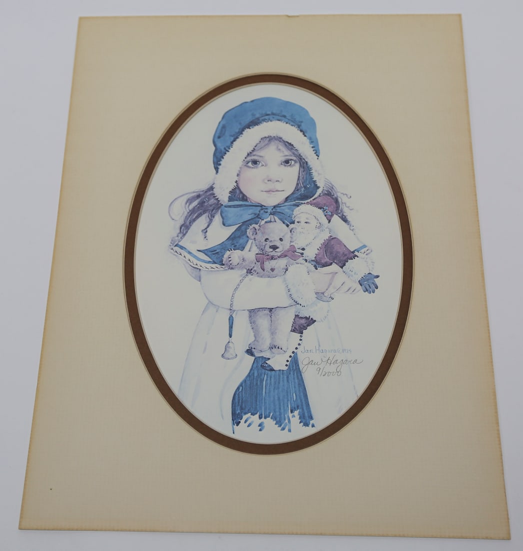 Jan Hagara Child with Toys Limited Edition Lithograph: A limited edition lithograph by Jan Hagara, depicting a young child in winter attire holding a teddy bear and Santa Claus doll. Signed and numbered 9 of 2000 and dated 1984. Presented with an oval mat