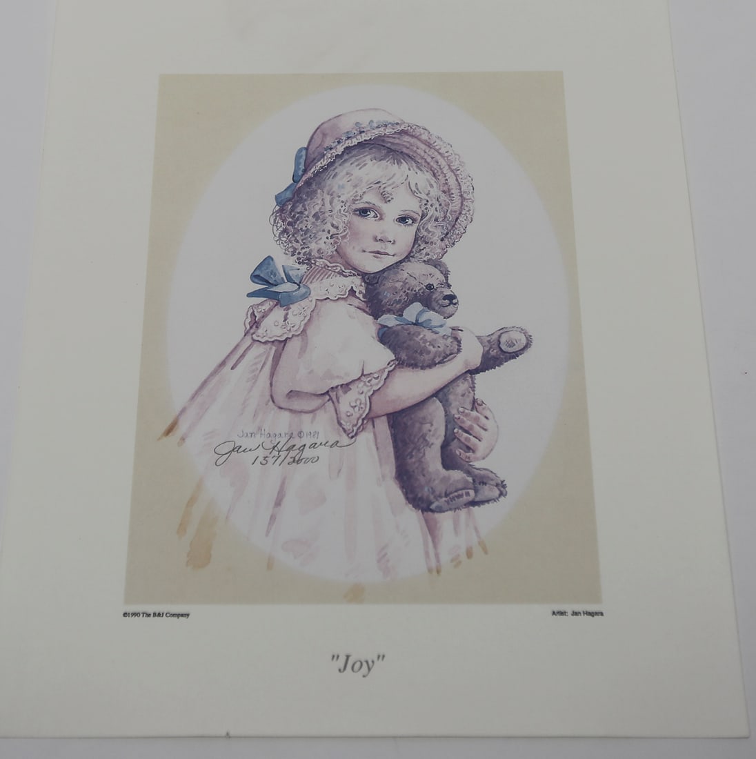 Jan Hagara Joy Limited Edition Lithograph: A limited edition lithograph by Jan Hagara titled Joy, depicting a young girl in a bonnet and lace-trimmed dress holding a teddy bear. Signed and numbered 137 of 2000, dated 1991, and published by the