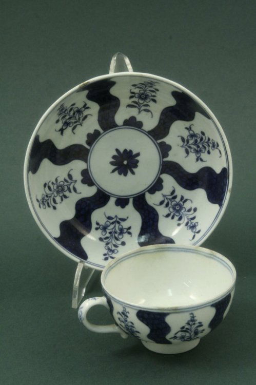 An 18th century Lowestoft cup and saucer,: An 18th century Lowestoft cup and saucer, painted Robert Brown pattern with radiating blue scale line and floral sprigs in underglaze blue, open crescent marks