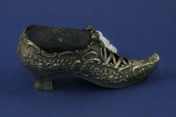 A late 19th century Continental white metal shoe: A late 19th century Continental white metal shoe pin cushion, possibly German, embossed with flowers and scrolls, 4.25ins