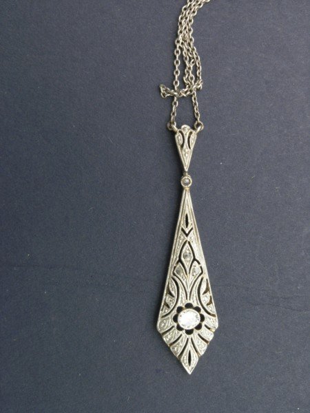 An Art Deco diamond set pendant,: An Art Deco diamond set pendant, the millegrain openwork with a central stone, on attached chain