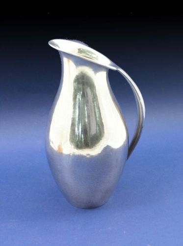 A Georg Jensen sterling silver pitcher designed b: A Georg Jensen sterling silver pitcher designed by Johan Rohde, of curvaceous form, with angled lip and curved handle, with lightly hammered decoration (small dent to base), 9ins