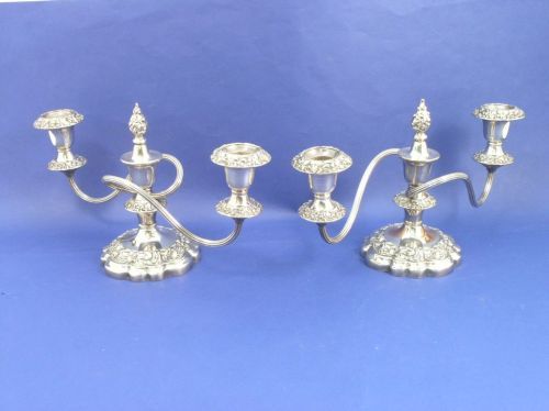 A pair of silver plate on copper two light candel: A pair of silver plate on copper two light candelabra, of squat form with reeded scrolling branches, centrally knopped stem on lobed base with floral and scroll decorated borders, 7.5ins