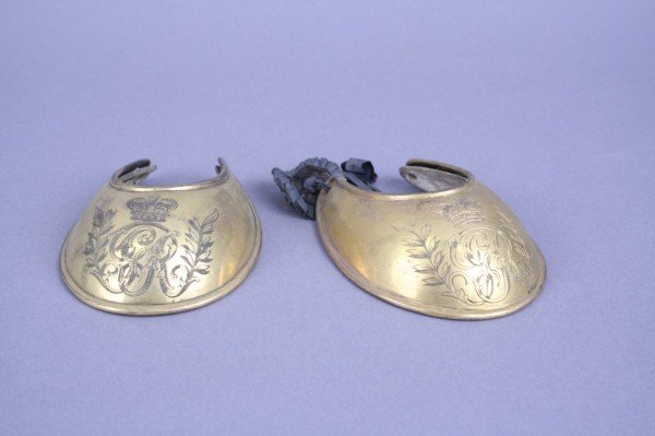 *A pair of George III brass gorgets: A pair of George III brass gorgets, engraved with a crowned cypher and laurels, 4.25ins THIS LOT IS SUBJECT TO 5% IMPORT DUTY ON THE HAMMER PRICE AND PREMIUM.