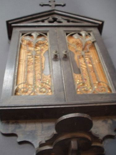 Two icons - Christ and Madonna and Child: An icon, depicting the face of Christ, in ebonised case, surmounted by a cross and pierced cornice over a pair of pierced metal doors, H 87cm W 37.5cm; and another icon, Madonna and Child, on metal pa