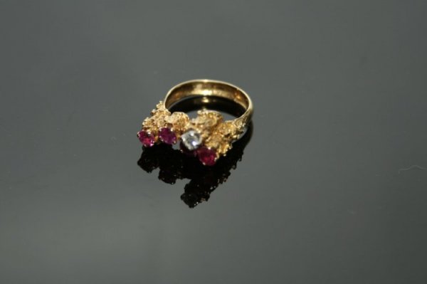 A ruby and diamond dress ring,: A ruby and diamond dress ring, four rubies and a diamond set in 18ct gold bark effect high mount, by Andrew Grima, size Q.