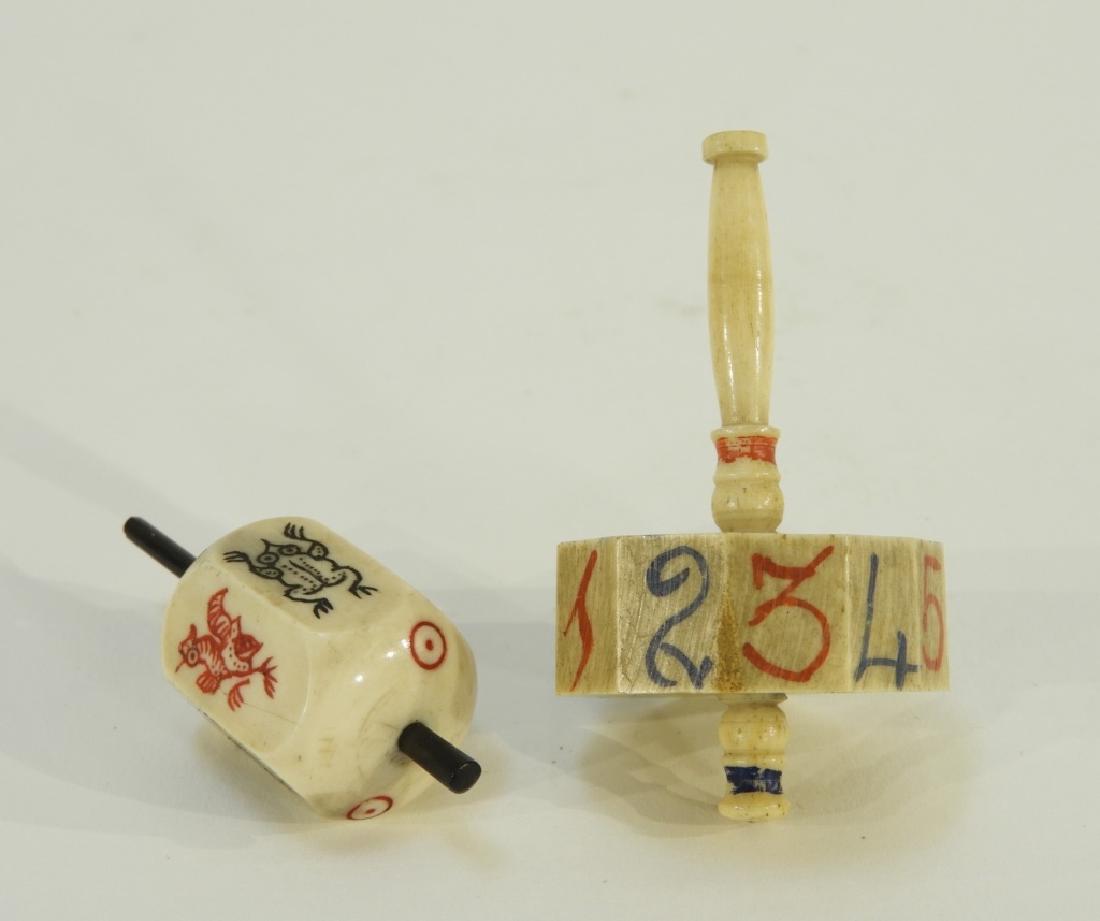 2 European Carved Bone Polychrome Teetotum: EUROPE, 19TH CENTURY Two European carved bone teetotum game pieces. The pieces are polychrome decorated, one polygonal with numerals 1 to 12, the other hexagonal with animals including a cat, frog, ra