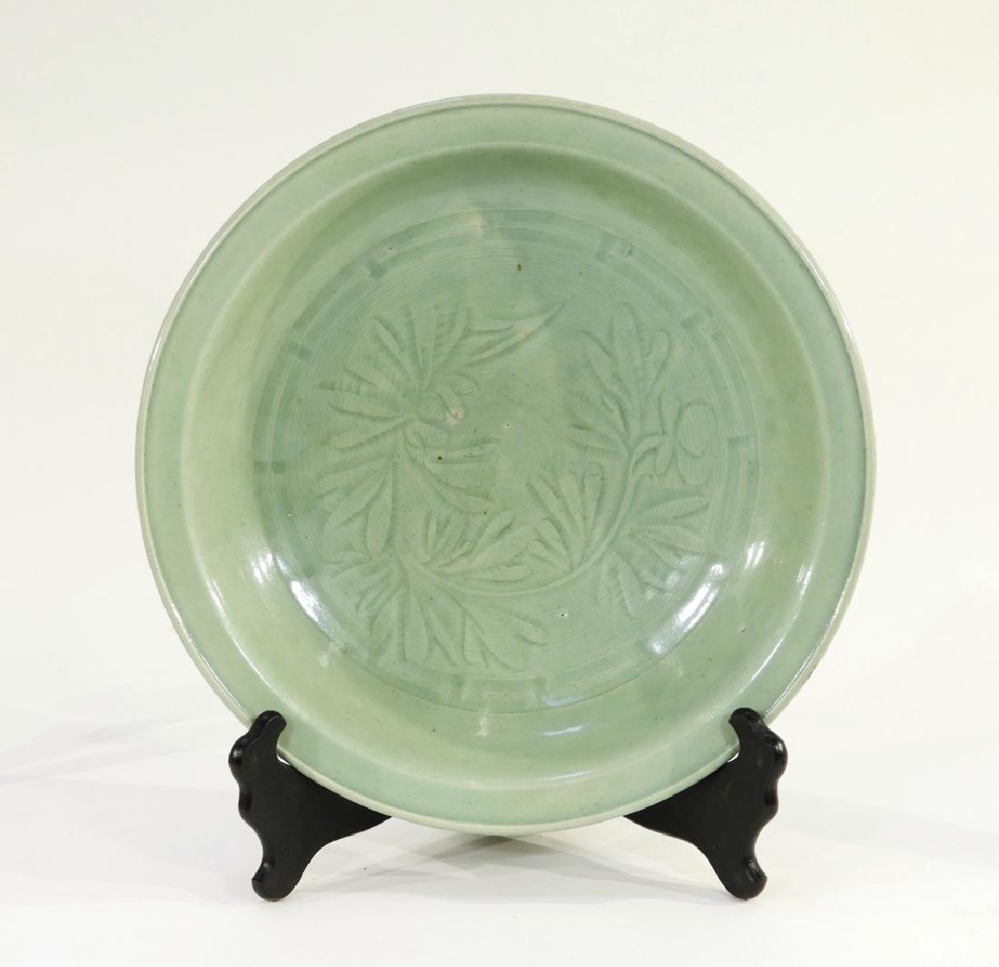 Chinese Ming Dynasty Longquan Celadon Bowl: CHINA, MING DYNASTY A fine Chinese Longquan celadon bowl. The bowl sits on a short foot rising into a shallow bowl with a raised beveled lip. The interior is decorated with an incised foliate motif. T