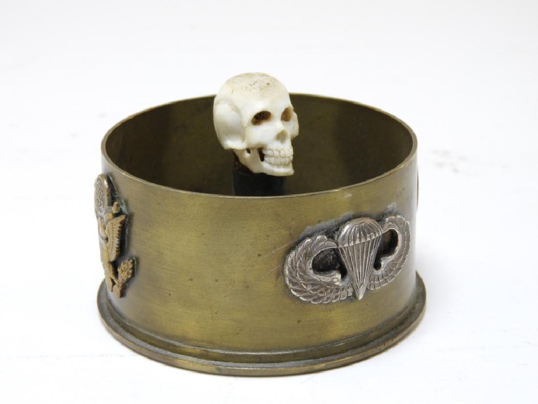 WWII U.S.Airborne Trench Art with Wings Lt Col Pin: European Campaign,1942-1945 A nice Trench Art shell, the Wings, Lt Colonel pin, Army Crest, and English Penny are all attached to the side. On the inside is a carved skull out of bone. Created from a