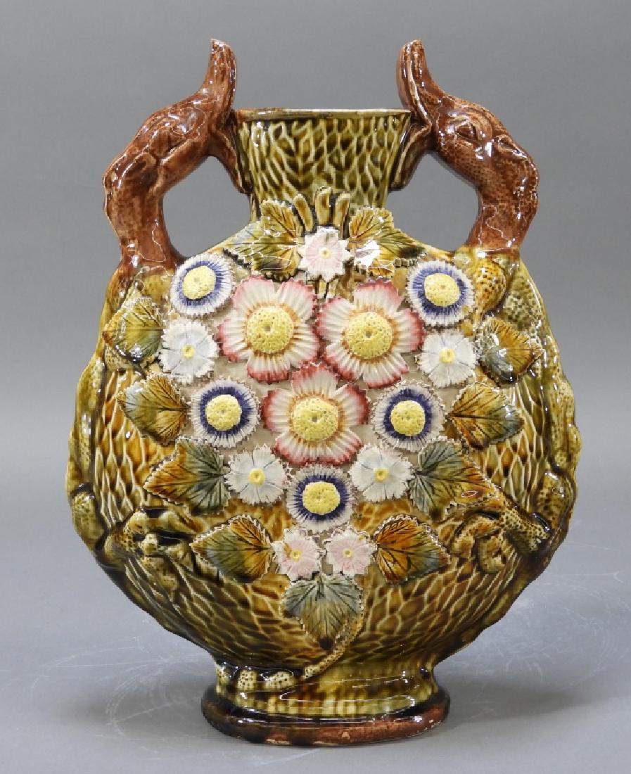 19C German Majolica Dragon Handle Moon Flask Vase: Germany,Late 19th century Moon flask form adorned with figural duck dragon lizard handles with central floral embellishments. Earthenware,13" tall, Minor craquelure, otherwise good condition. From the