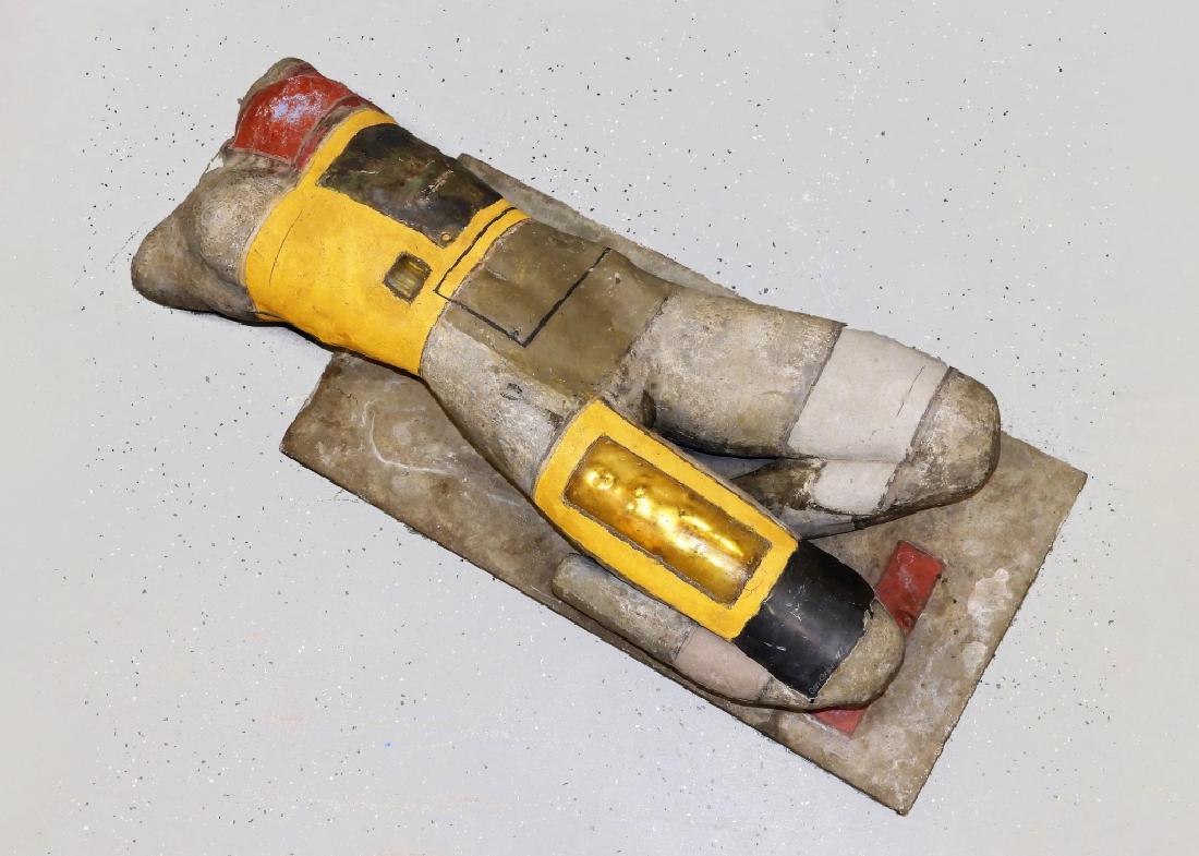 Dan Corbin Post-Modern Figurative Female Sculpture: Alabama b. 1947 Molded and sculpted of Bauxite, reclining female nude with polychrome painted geometric design. The torso is inset with three bullets and wrapped with sheet steel. The upper thigh is i