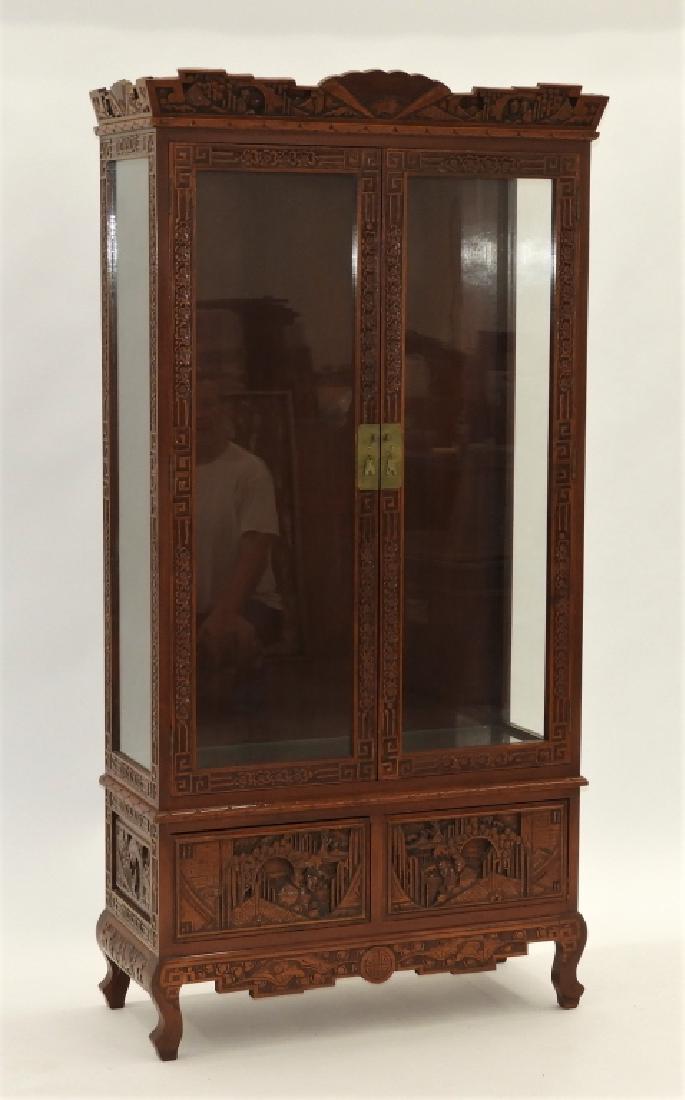 Chinese Carved Hardwood China Display Cabinet: China,20th Century Carved crest with landscape designs over two doors with two adjustable glass shelves over two drawers upon a scrolled foot base, attributed to J.L. George Company. Hardwood,74" x 36