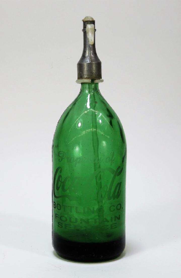 Coca-Cola Fountain Service Seltzer Green Bottle: United States,Early 20th CenturyEmerald green fountain service seltzer bottle etched "Property of Coca Cola Bottling Co. Fountain Service".Glass, metal,13 3/4" tall x 4" dia.,From the collection of Ru