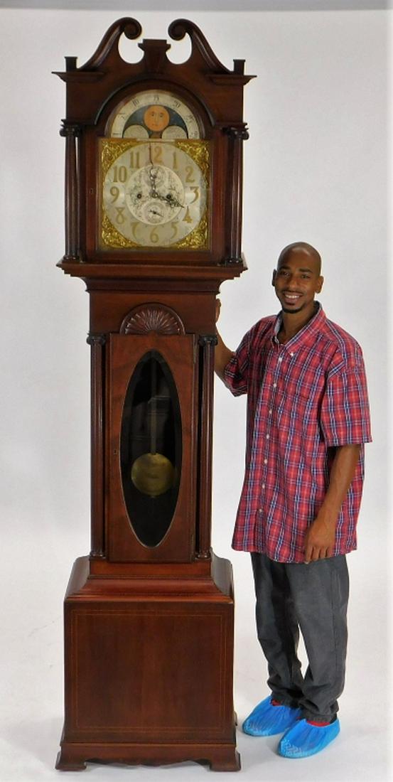 Smith Patterson Co Boston Mahogany Tall Case Clock: ,Massachusetts,Early 20th Century Arabic numeral dial with two subsidiary dials and moon phase within a Corinthian column hood over a shell carved case with string inlay and beveled glass door. Mahoga