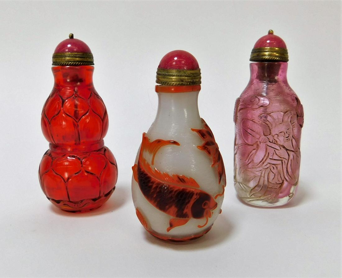3PC Chinese Peking Glass Overlay Snuff Bottles: ,China,20th Century Includes a black over orange over white Peking glass snuff bottle with koi fish, a red bottle with floral petal decoration, and a pink bottle decorated with an old man amongst tree