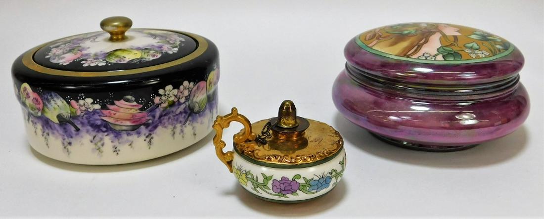 3PC American Belleek Porcelain Powder Jar Oil Lamp: ,United States,20th Century Includes an Orientalist powder jar with fans and paper lanterns, an art nouveau powder jar with Mucha-esque woman in iridescent enamel, and a handheld oil lamp with red, ye
