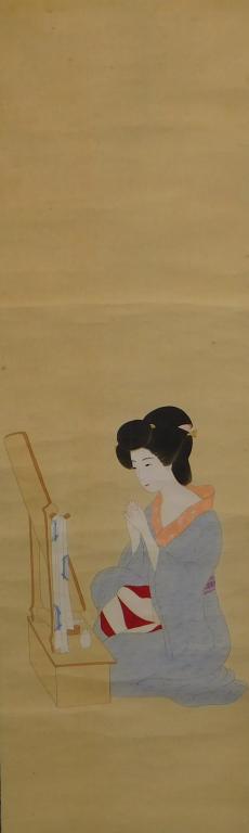 Japanese Geisha Interior Genre Hanging Wall Scroll: Japan, Dressed in a pale blue kimono sitting in front of a vanity against a deep blue and gold silk mount. Ink, paper, silk Overall 71 1/2" x 19 3/4",Image 47 1/2" x 14 1/2" Spanning 250 years of Japa