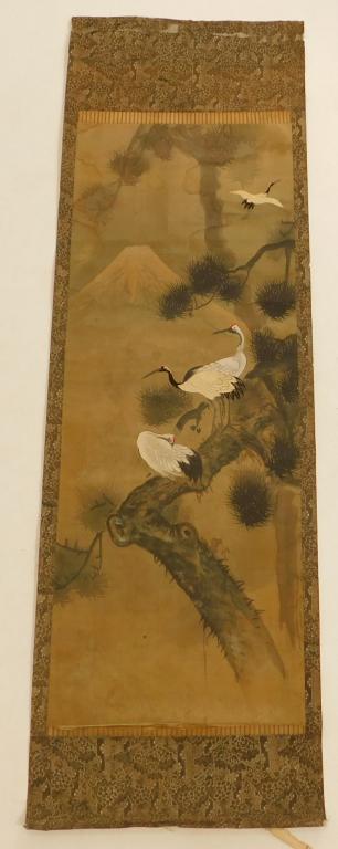 Japanese Painted Cranes Hanging Wall Scroll: Japan,Meiji Period Bird and flower style painting with three birds perched atop a pine branch with a mountain in the background. The cranes to the center and in flight are embroidered. Paper, silk,59"