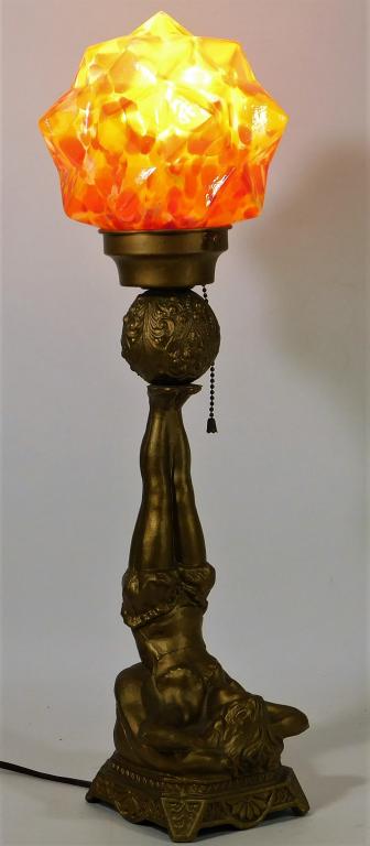 Spelter Art Deco Bohemian Czech Glass Dancer Lamp: Bohemia,20th Century Spiked sphere shade with red, yellow, and orange splatter supported by a figural base of a woman lying on her back supporting the shade with her feet. Metal, glass,22 1/2" x 6 1/2