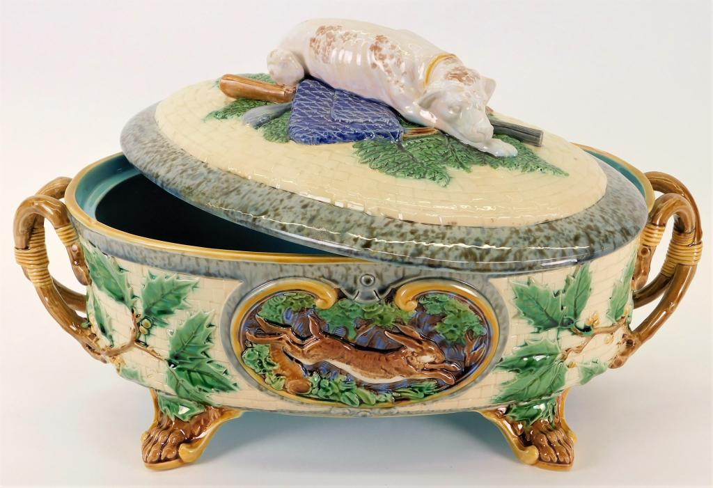 Minton Majolica Hunting Dog Game Tureen: England,Late 19th Century Figural sleeping dog handle atop a blue coat and rifle lid with leaping rabbit, pheasant, and foliage decorations across the bowl body supported by four claw feet. Pottery,9"
