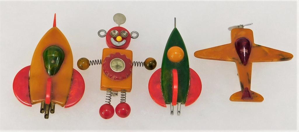 4 MCM Bakelite Robot Aircraft Brooch Jewelry Group: United States,Circa 1960 Includes two orange, green, and red rocket ship brooches, one yellow and red airplane brooch, and one red an yellow robot compass brooch. Plastic, metal,Smallest 2" x 2 1/2",L