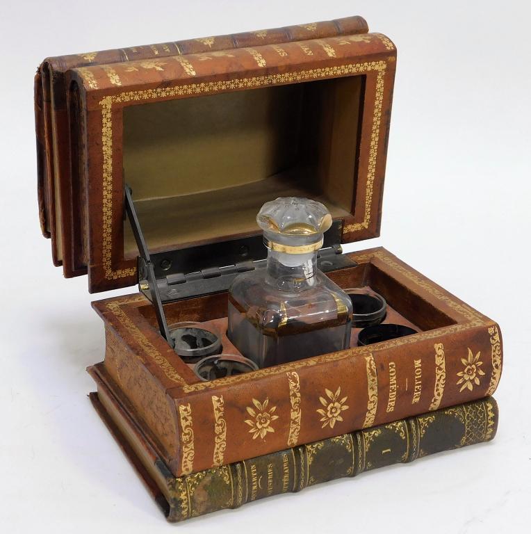 19C French Victorian Book Safe Decanter Set: France,Late 19th Century Stack of five leather bound books opening to reveal five compartments with one decanter with gilt decoration and cut glass stopper and three diminutive tumblers. Leather, glas
