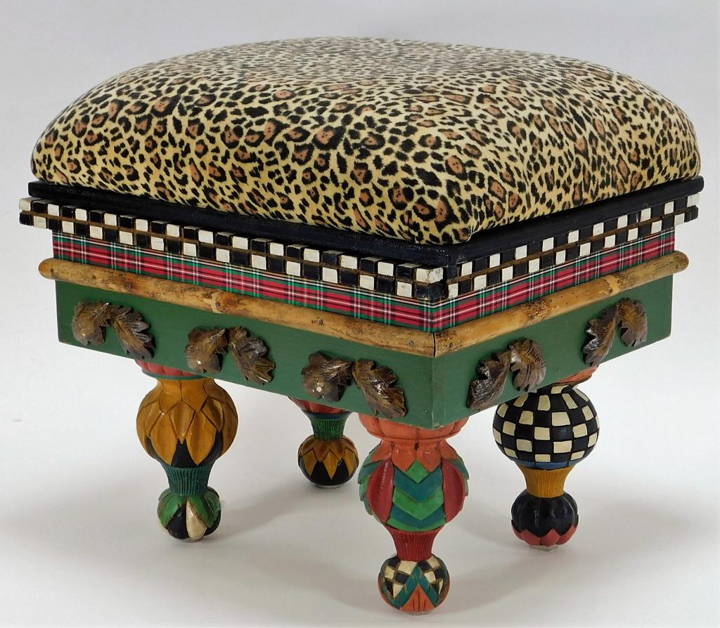 MacKenzie-Childs Whimsical Carved Foot Stool: New York,20th Century Colorful stool with leopard pint top and interior storage over a checkered plaid and leaf decorated body on four uniquely carved legs. An interesting piece of modern interior des