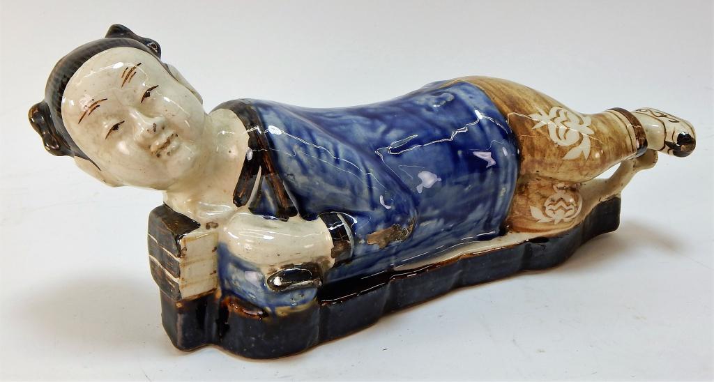 Chinese Chizou Ware Female Porcelain Pillow: ,China,20th Century Depicts a reclining female laying on bed wearing a blue robe and brown floral pants with traditional shoes. Unglazed base. 17" long,